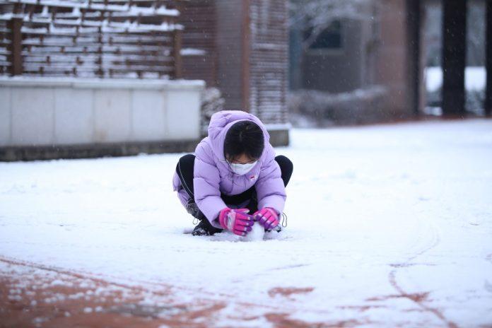 Bé gái hào hứng ngồi xổm giữa sân chơi trò nặng hình người tuyết nhỏ (Ảnh: Internet).