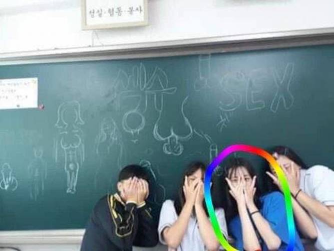 Kim Garam (áo xanh khoanh tròn) chụp trước tấm bảng vẽ hình tục tĩu (Nguồn: Internet)
