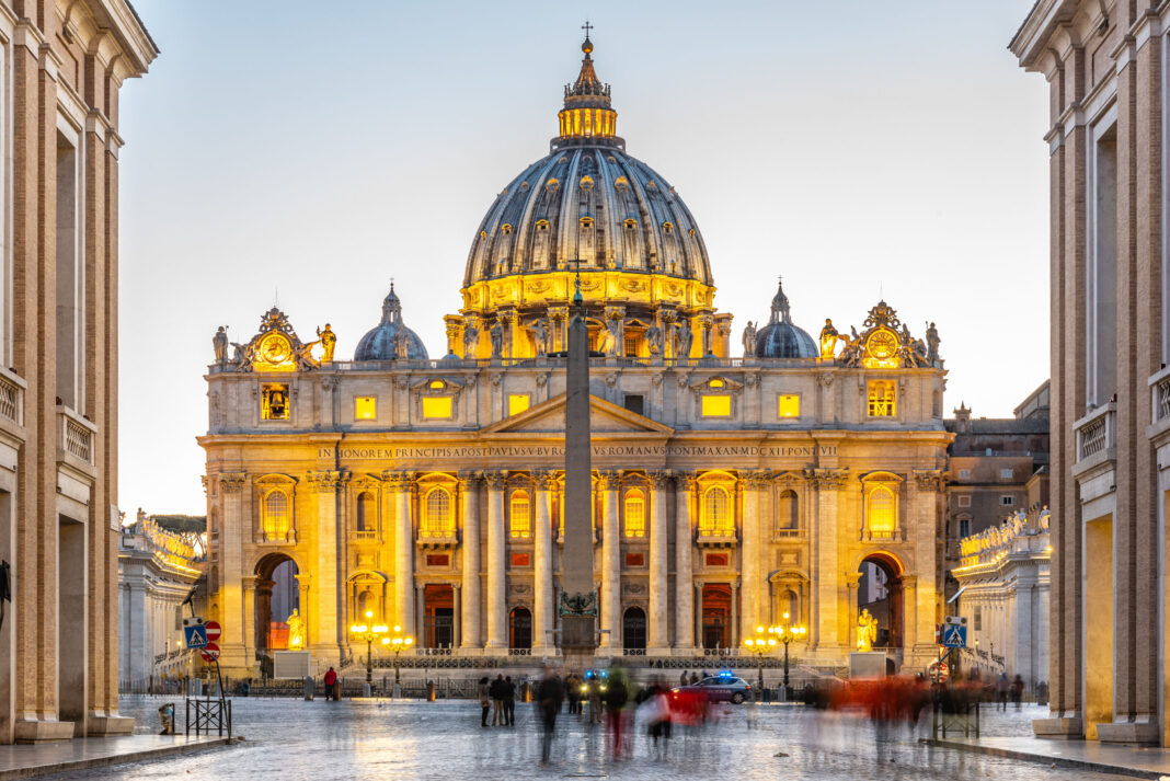 Vatican City by night. Illuminated dome of St Peters Basilica and St Peters Square at the end of Via della Conciliazione. Rome, Italy